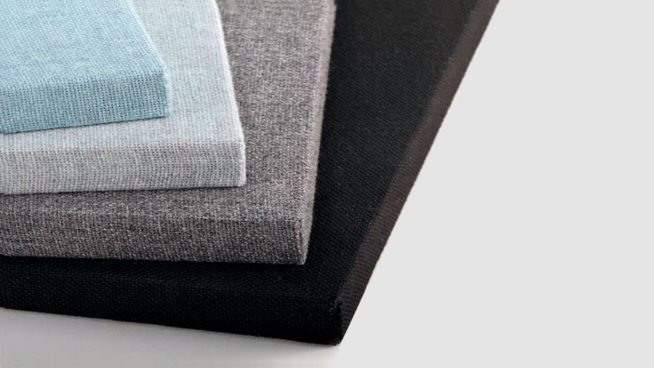 Four rectangular fabric-covered panels are stacked on top of each other. The panels are light blue, light gray, medium gray, and black, displayed from top to bottom against a light background.