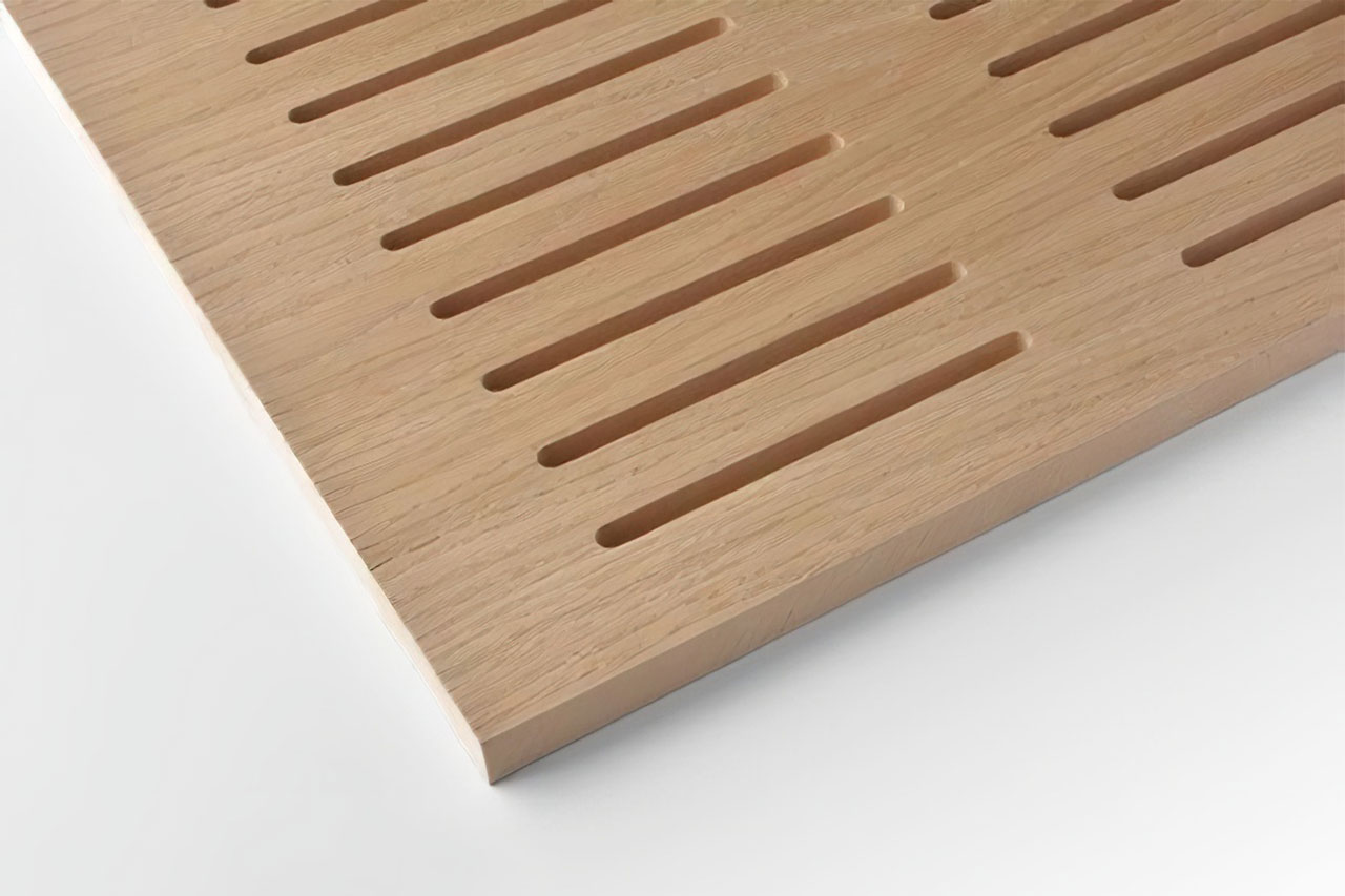 A close-up of a light wooden panel with evenly spaced, parallel rectangular slots cut into the surface, shown on a white background.