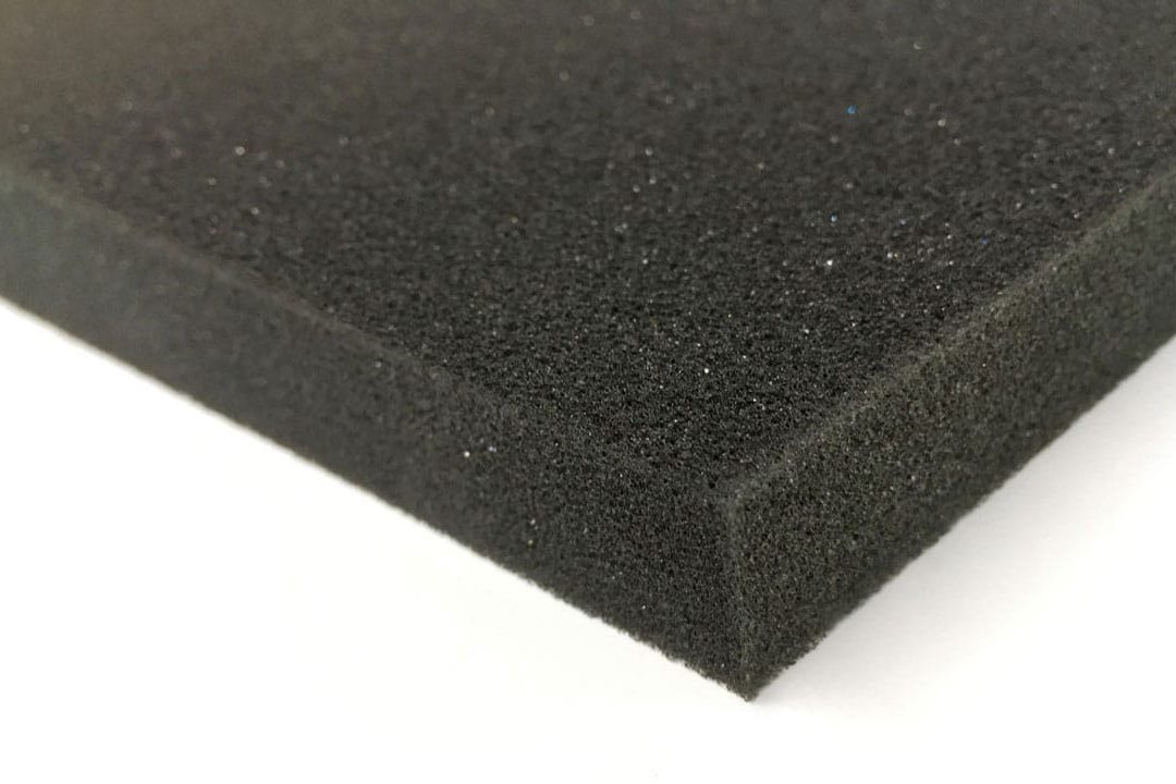 A close-up view of a rectangular piece of black foam with a textured surface, shown lying flat against a white background.