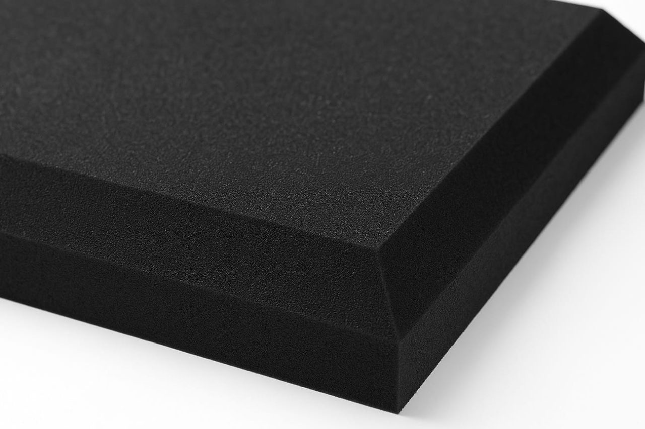 A close-up of a rectangular piece of black foam with squared edges and a beveled side, photographed against a white background.