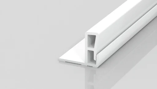 A white, rectangular plastic or metal strip with hollow sections and a notched base, placed on a reflective, light gray surface.