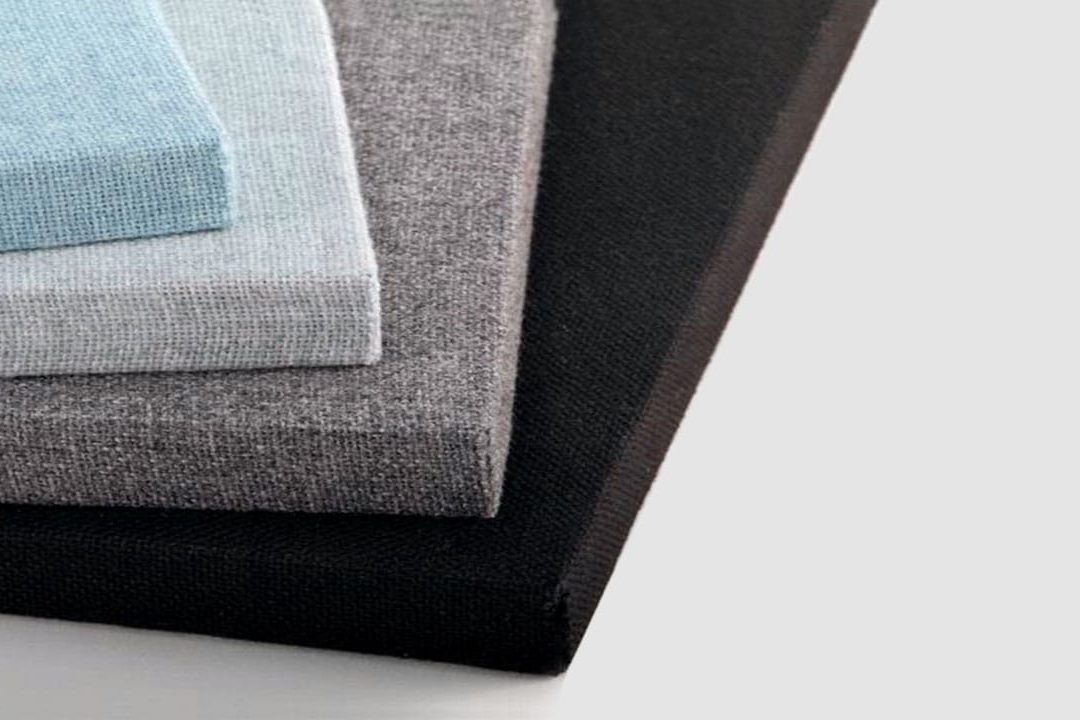 Four rectangular fabric-covered panels are stacked on top of each other. The panels are light blue, light gray, medium gray, and black, displayed from top to bottom against a light background.