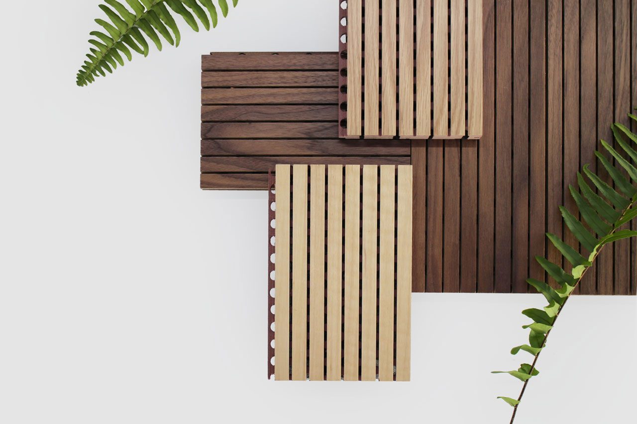 Three wooden surfaces with different slat patterns overlap at right angles, surrounded by green fern leaves on a white background. The wooden surfaces vary in color from light to dark brown.
