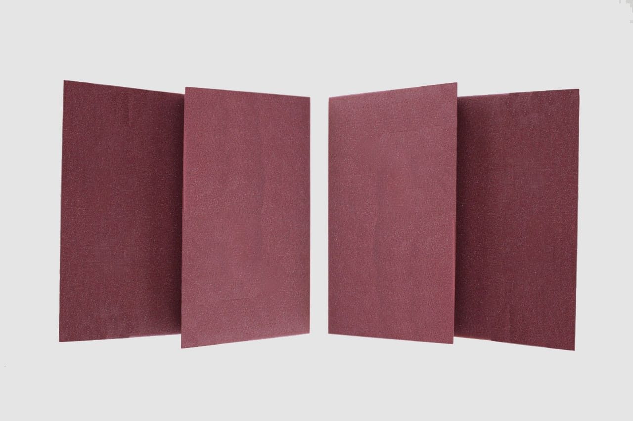 Four rectangular sheets of reddish-brown sandpaper are arranged upright in pairs against a plain white background.