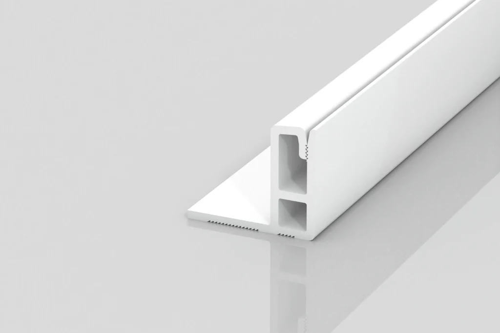 A white, L-shaped plastic trim piece with two rectangular inner channels, shown on a glossy, light gray surface. The trim has one long flat section and one upright section forming a right angle.