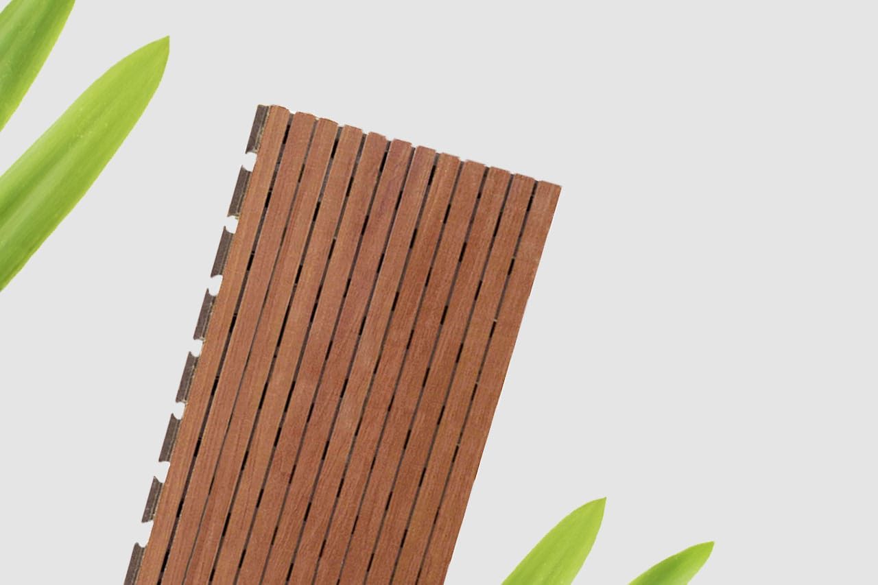 A rectangular wooden slat panel is placed diagonally on a white background, with green leaves visible in the top left and bottom right corners.