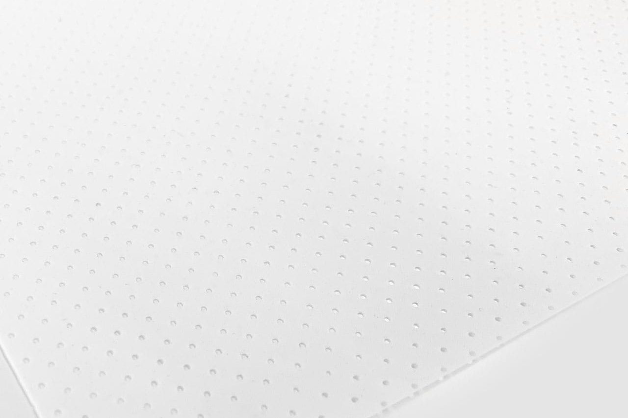 A close-up of a white textured surface with an array of small, evenly spaced holes arranged in a grid pattern, creating a subtle geometric design.