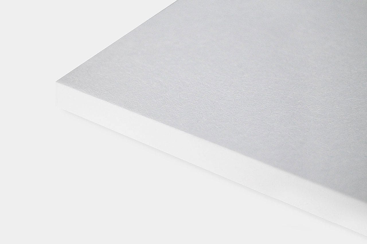 A close-up view of the corner of a white, rectangular sheet of paper on a light gray background.