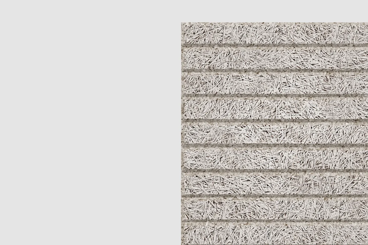 Close-up view of a textured, rectangular surface with horizontal rows made of interwoven, light-colored fibers, resembling a natural or synthetic mat. The background is plain light gray.