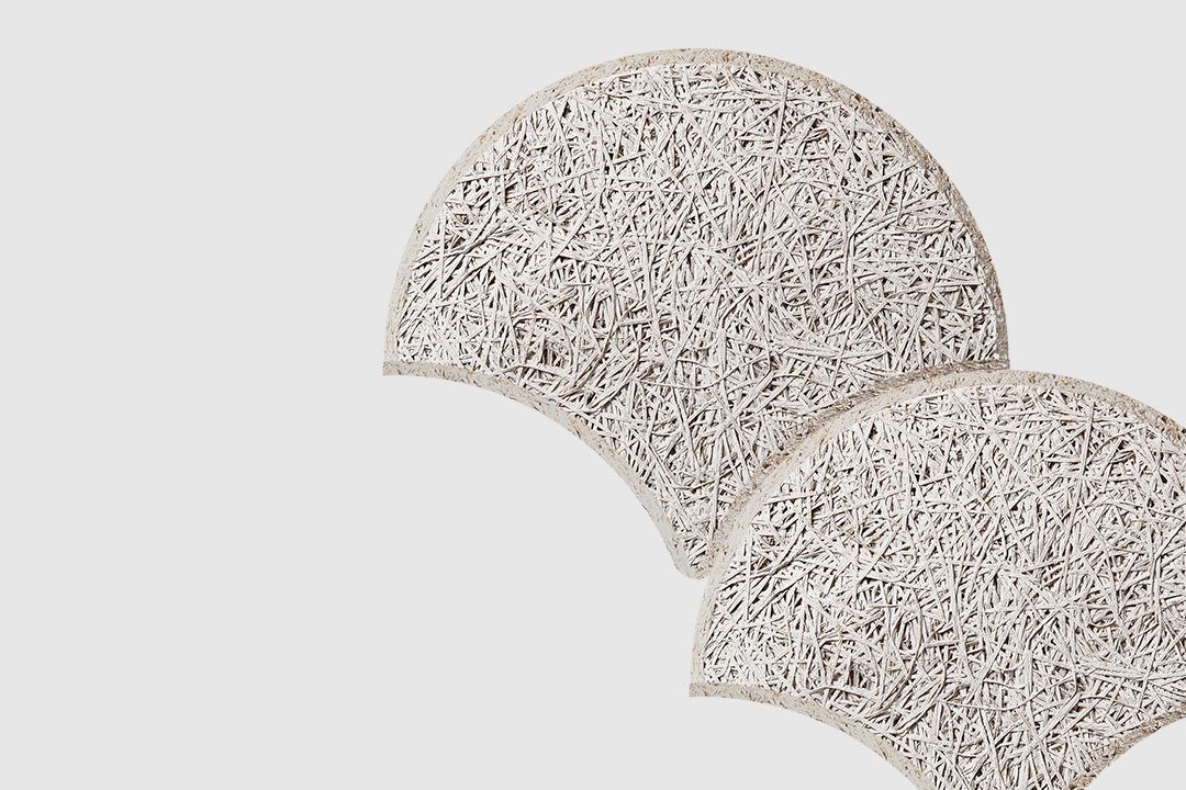 Two textured, semi-circular panels with a rough, fibrous surface overlap slightly on a plain, light background. The panels appear off-white and have an organic, woven appearance.